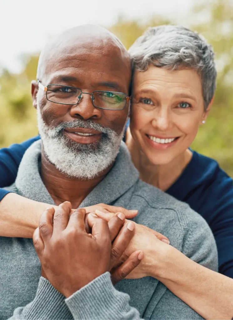 A joyful older couple embraces outdoors.